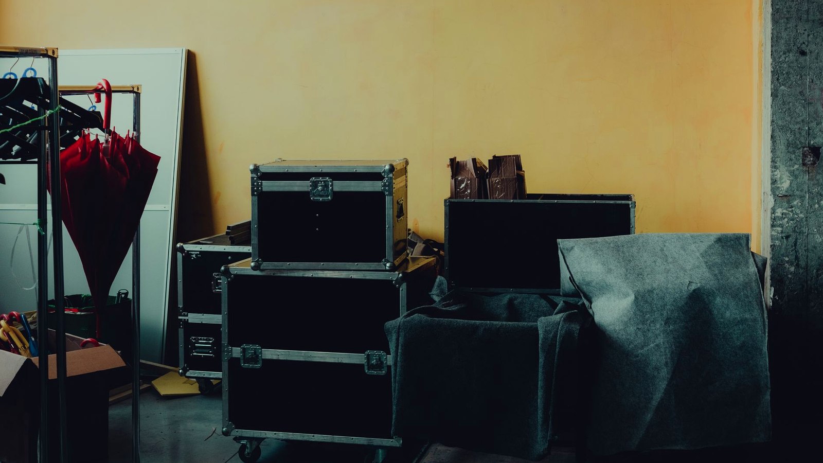 Event warehouse interior: numbered flight cases, folded tables against a wall, LED fixtures lined up on stands.