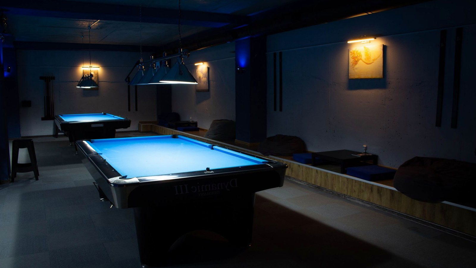 Salle de réception préparée pour une soirée à thème : tables nappées de feutre, éclairage dirigé, personnel en tenue de service.