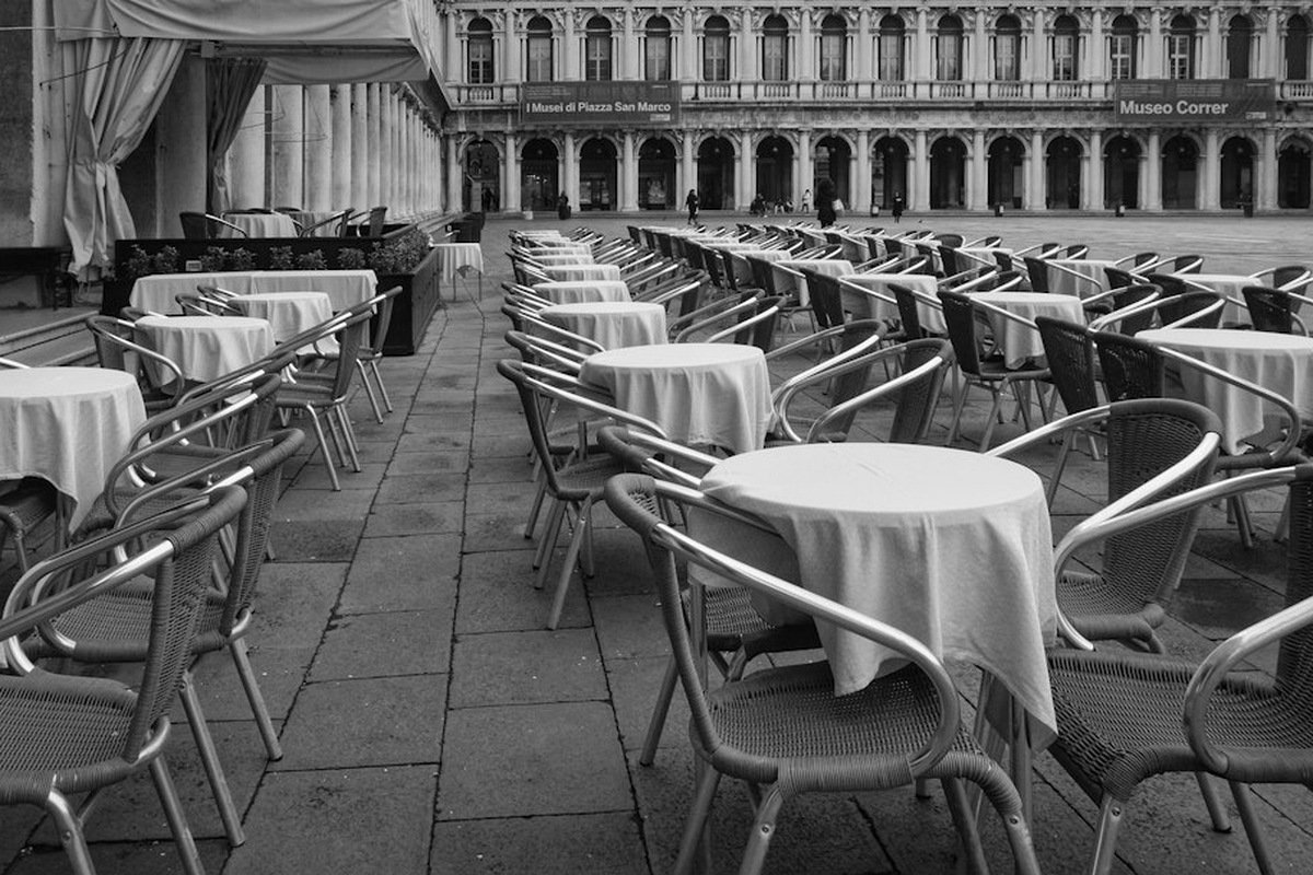 Large room laid for a gala dinner: round tables with cloths, a lit stage in the background.